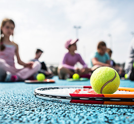 Tennis racket and ball close up, children in the backgrond
